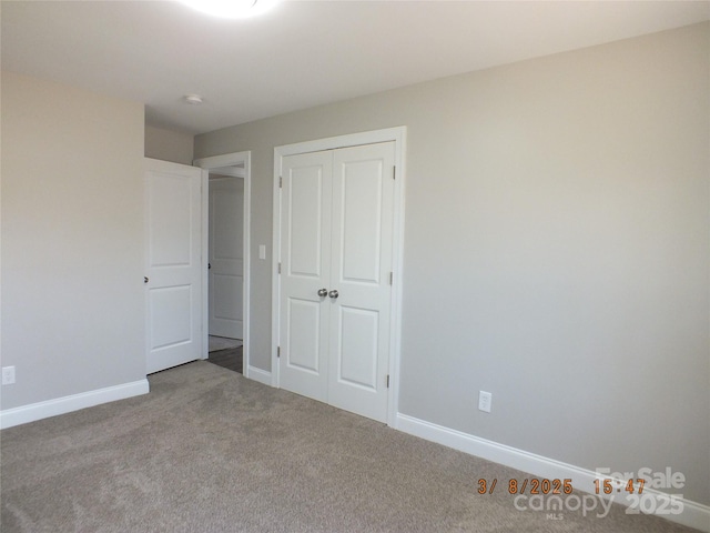 unfurnished bedroom with a closet, carpet flooring, and baseboards