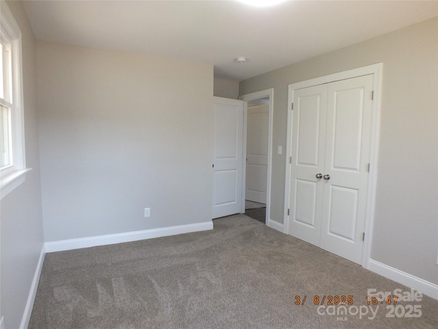 unfurnished bedroom featuring a closet, baseboards, and carpet flooring