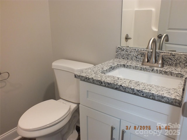 bathroom featuring toilet, baseboards, and vanity