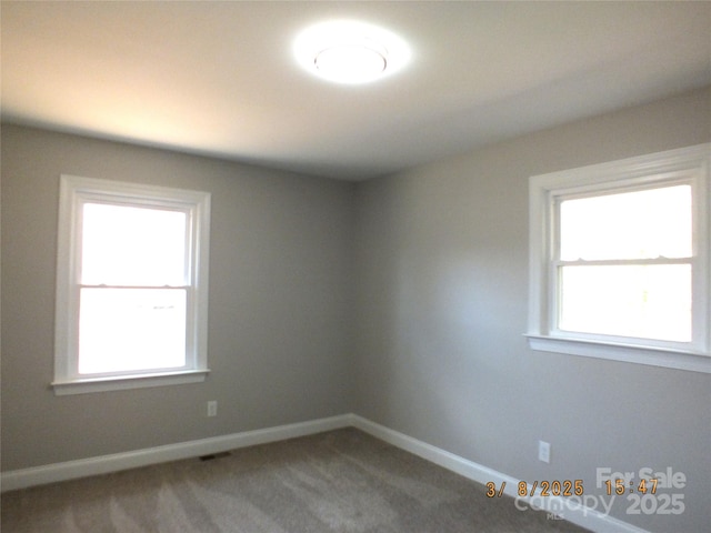 carpeted spare room featuring visible vents and baseboards