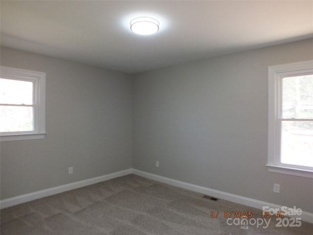 unfurnished room featuring a healthy amount of sunlight, light carpet, and baseboards