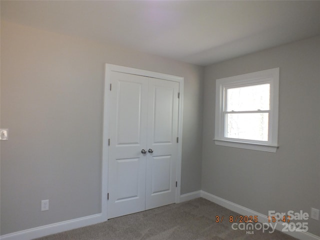 unfurnished bedroom featuring a closet, carpet flooring, and baseboards