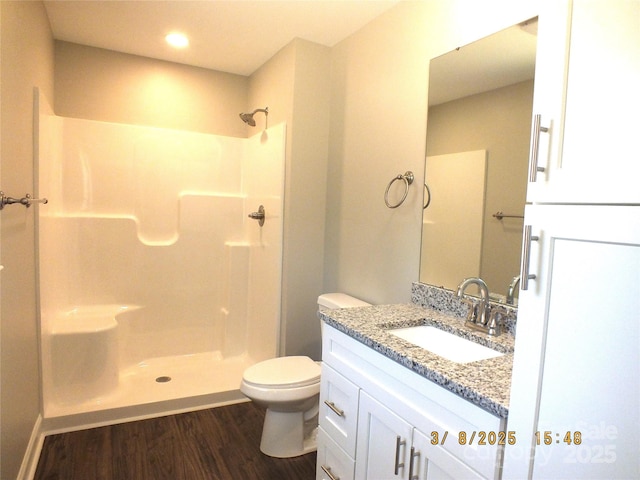 bathroom featuring vanity, walk in shower, wood finished floors, and toilet