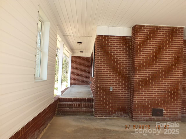 interior space with wooden ceiling, brick wall, and concrete flooring