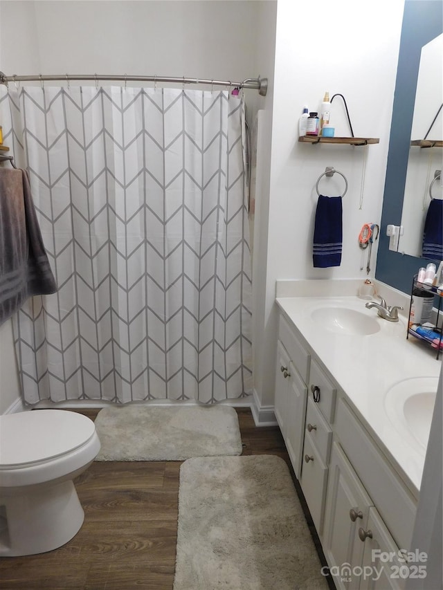 bathroom with a shower with curtain, double vanity, a sink, and wood finished floors