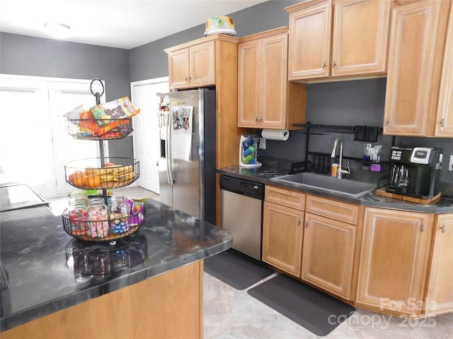 kitchen with light brown cabinets, dark countertops, appliances with stainless steel finishes, and a sink