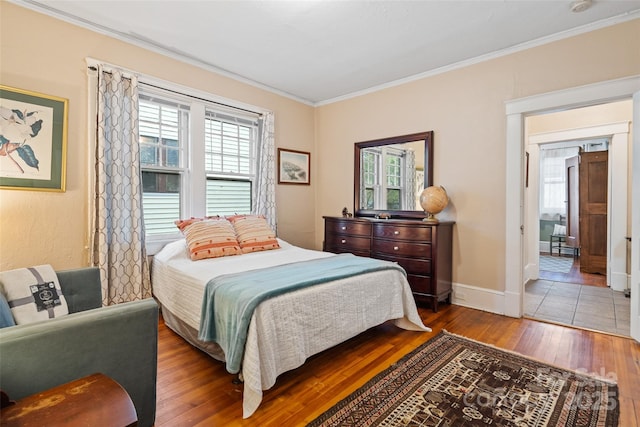 bedroom with crown molding, wood-type flooring, and baseboards