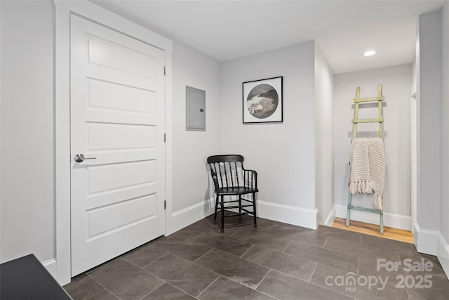 living area with baseboards, electric panel, and recessed lighting
