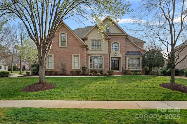 view of front of home with stucco siding, brick siding, and a front lawn