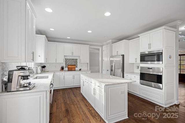 kitchen with decorative backsplash, white cabinetry, stainless steel appliances, and a sink