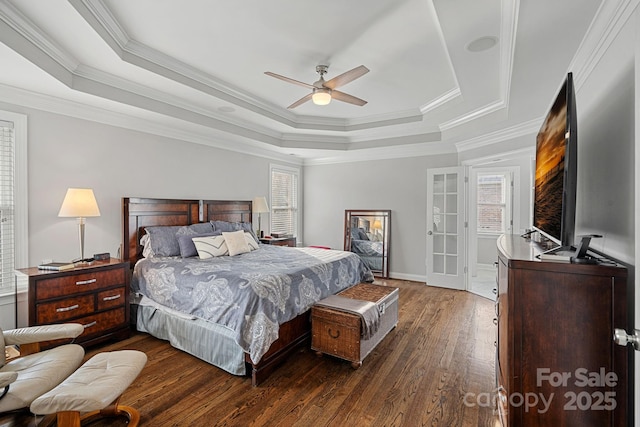 bedroom featuring crown molding, baseboards, dark wood finished floors, a tray ceiling, and a ceiling fan