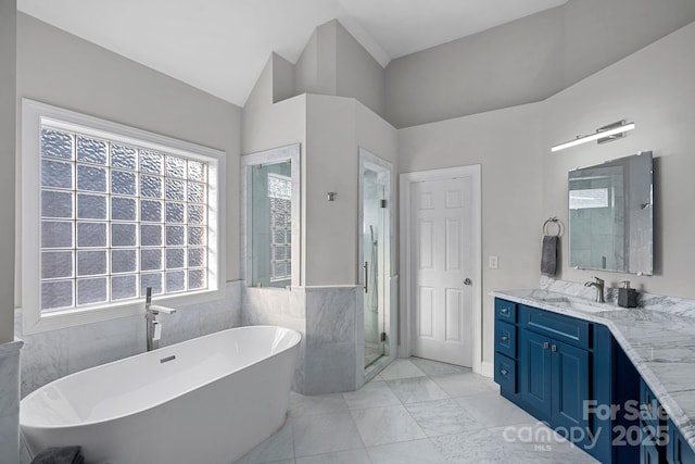 bathroom with vanity, a soaking tub, a shower stall, vaulted ceiling, and tile walls