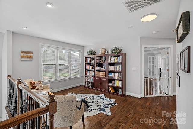 living area featuring visible vents, an upstairs landing, baseboards, and wood finished floors