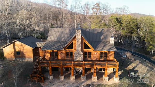 back of property featuring metal roof, stairway, a chimney, and a standing seam roof