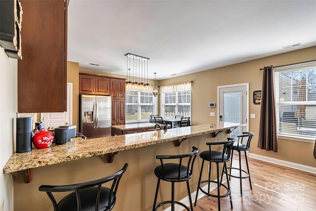 kitchen featuring plenty of natural light, stainless steel fridge with ice dispenser, visible vents, and light wood finished floors