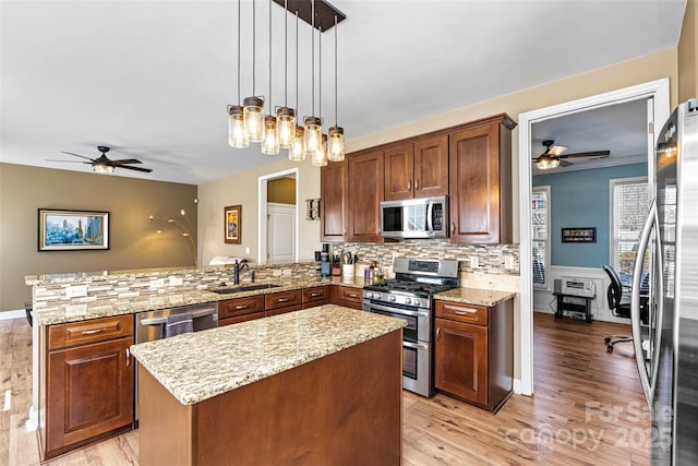 kitchen with a center island, decorative backsplash, a peninsula, stainless steel appliances, and a sink