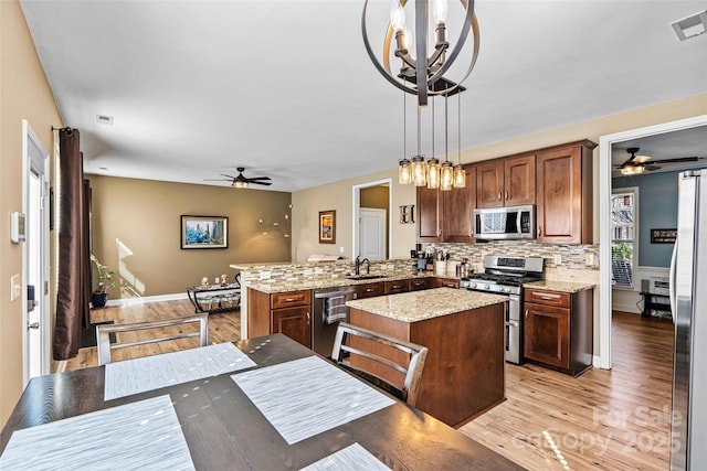 kitchen featuring visible vents, a peninsula, a sink, stainless steel appliances, and light wood-type flooring