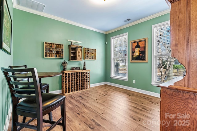 sitting room with crown molding, wood finished floors, visible vents, and baseboards