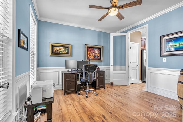 office space with crown molding, a ceiling fan, light wood-type flooring, and wainscoting