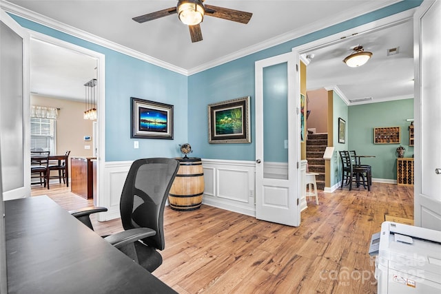 office area featuring a wainscoted wall, ceiling fan, crown molding, and light wood finished floors