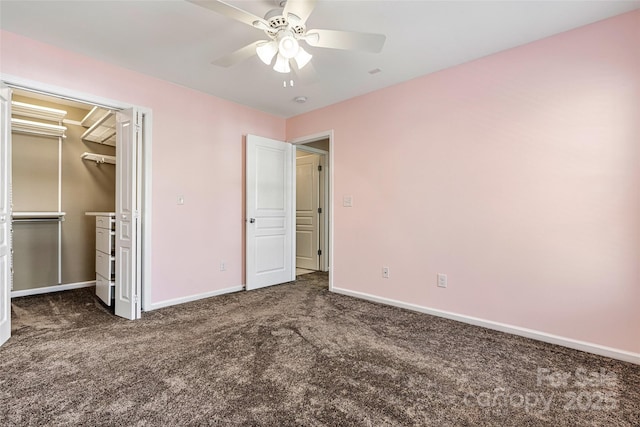 unfurnished bedroom featuring a spacious closet, carpet flooring, baseboards, and ceiling fan