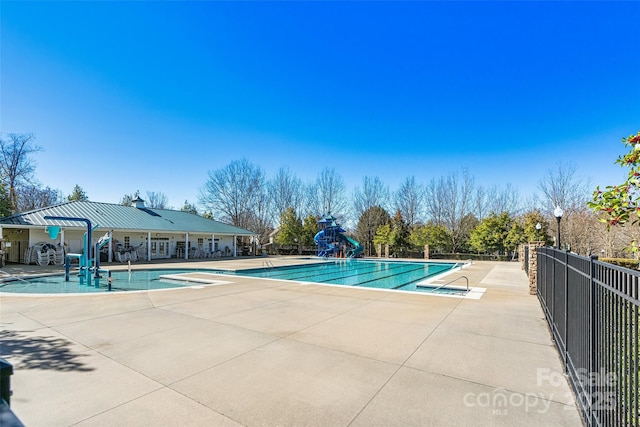 pool with fence, a water slide, and a patio area