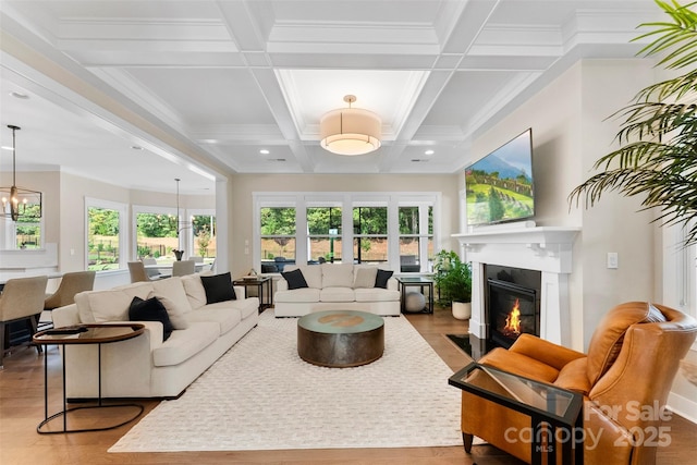 living room with an inviting chandelier, a fireplace with flush hearth, a wealth of natural light, and wood finished floors