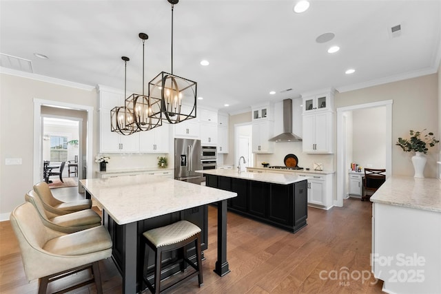 kitchen featuring a sink, ornamental molding, appliances with stainless steel finishes, a large island, and wall chimney exhaust hood