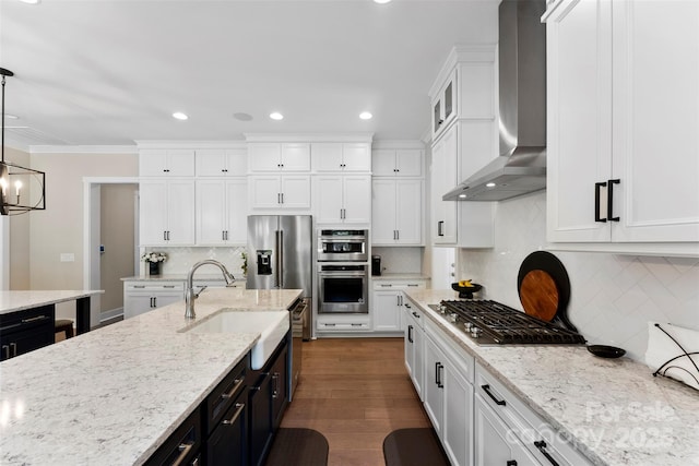 kitchen with white cabinets, dark wood finished floors, stainless steel appliances, wall chimney range hood, and a sink