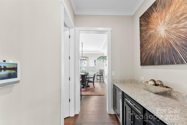 corridor with a notable chandelier, dark wood-style flooring, and crown molding