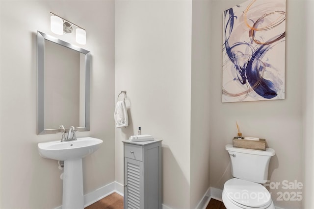 bathroom featuring toilet, baseboards, and a sink