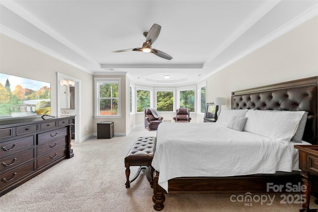 bedroom featuring a tray ceiling, light colored carpet, ceiling fan, ensuite bath, and baseboards