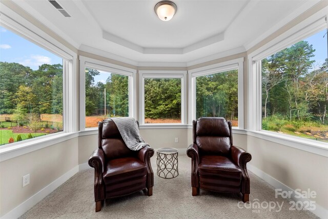 sunroom with visible vents, a raised ceiling, and a wealth of natural light