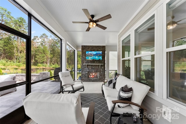 sunroom with ceiling fan and a fireplace