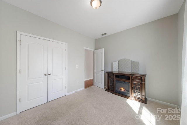 interior space with visible vents, carpet floors, baseboards, and a glass covered fireplace