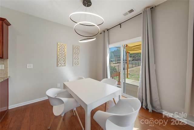 dining space featuring visible vents, baseboards, wood finished floors, and a chandelier