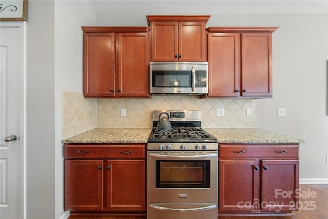 kitchen featuring tasteful backsplash, dark brown cabinets, appliances with stainless steel finishes, and light stone counters