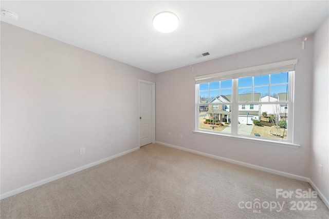 empty room with visible vents, baseboards, and light colored carpet