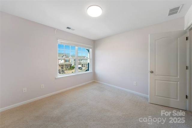 spare room with carpet, visible vents, and baseboards