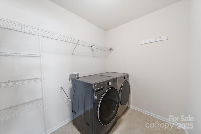 clothes washing area featuring baseboards, laundry area, and washing machine and clothes dryer