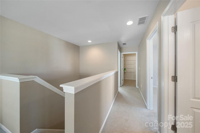 hallway with baseboards, visible vents, recessed lighting, light carpet, and an upstairs landing