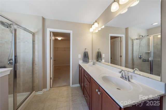 bathroom featuring tile patterned floors, double vanity, a stall shower, and a sink