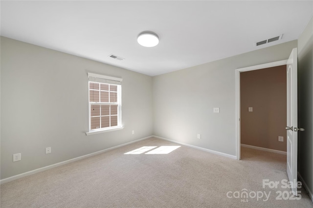 carpeted empty room featuring baseboards and visible vents