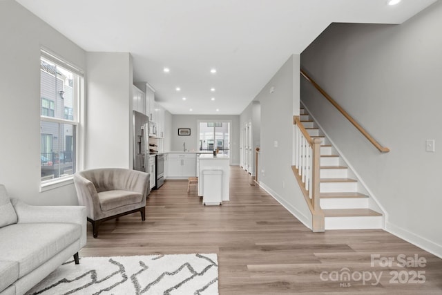 living area with stairs, baseboards, light wood-style flooring, and recessed lighting