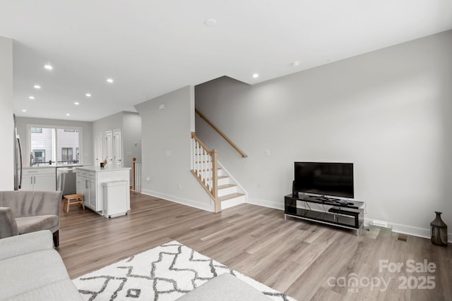 living area with light wood-style flooring, recessed lighting, and stairway