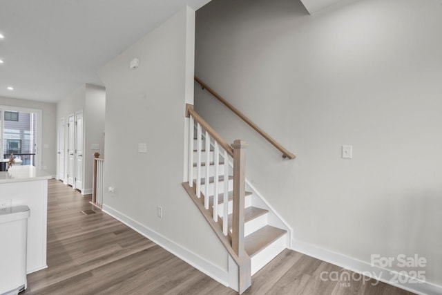 staircase featuring recessed lighting, baseboards, and wood finished floors