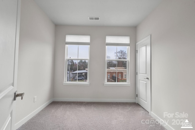 unfurnished room with carpet flooring, visible vents, and baseboards