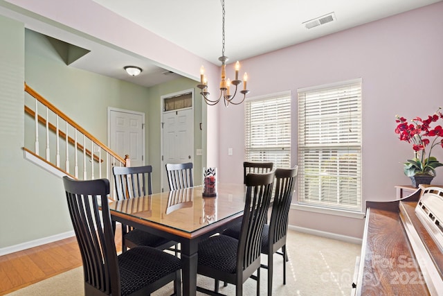 dining area featuring an inviting chandelier, stairway, baseboards, and visible vents