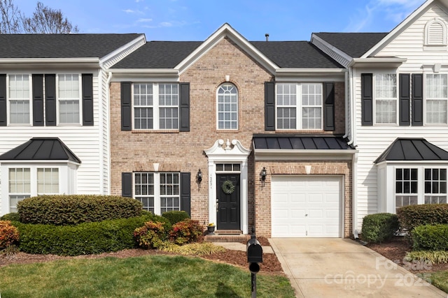 townhome / multi-family property with driveway, roof with shingles, a standing seam roof, a garage, and brick siding