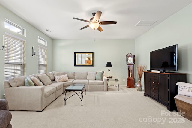 living area with visible vents, light colored carpet, baseboards, and ceiling fan